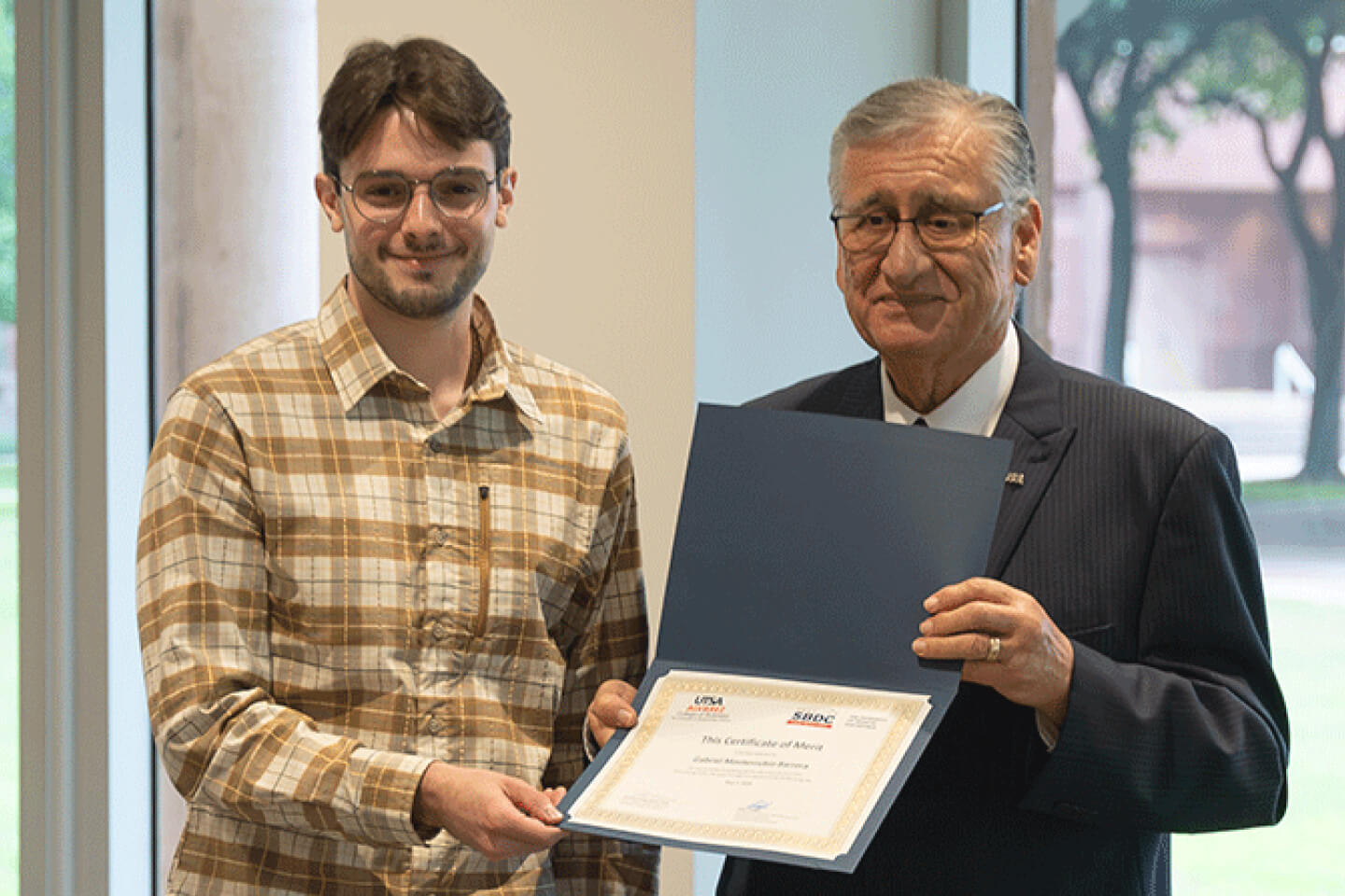 Student receiving his diploma from a leader of the school