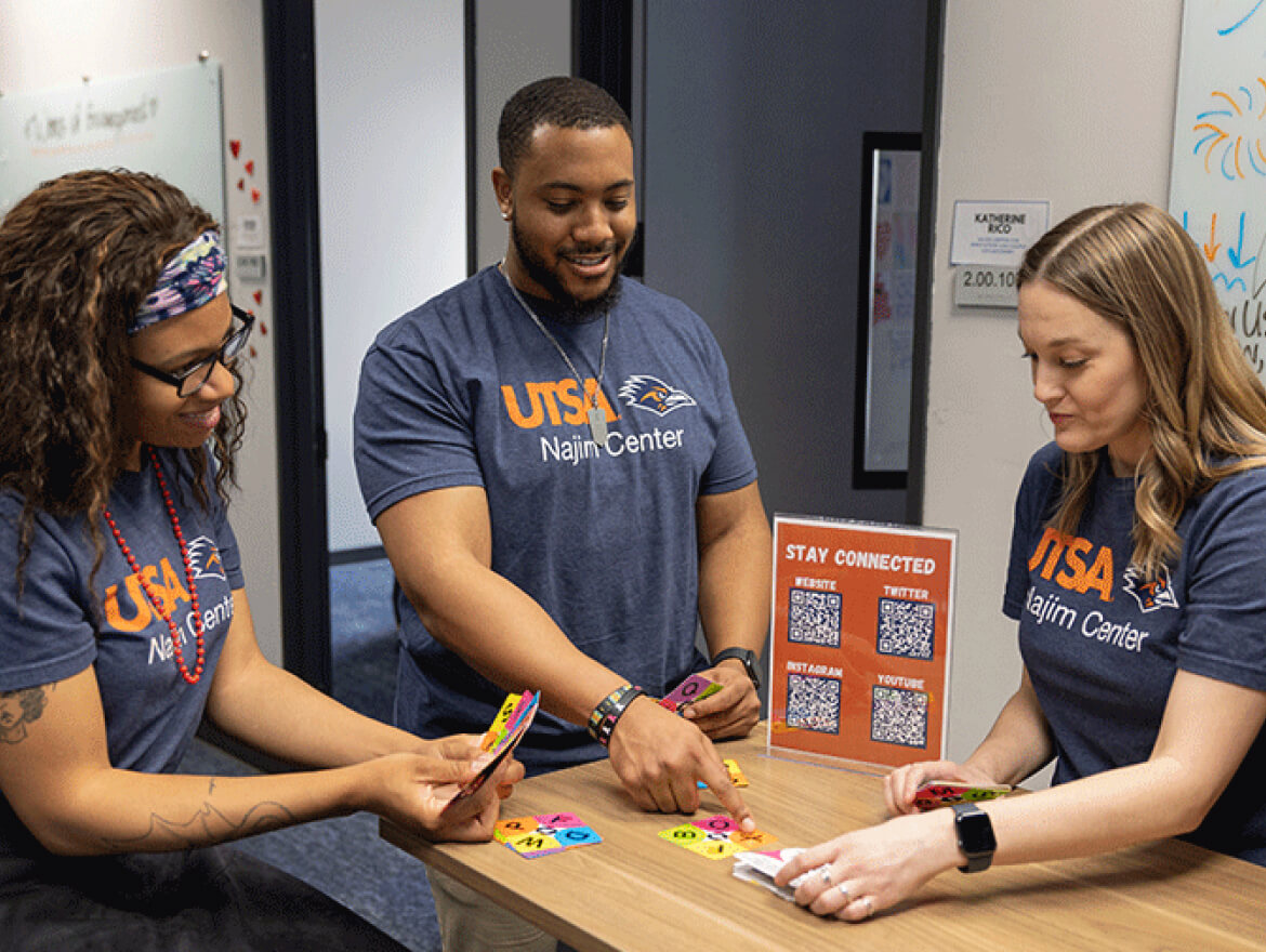 3 students playing a board game together at the Najim Center.