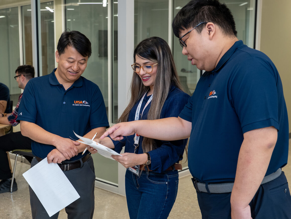 Female student looking at a manual with her 2 male instructors.