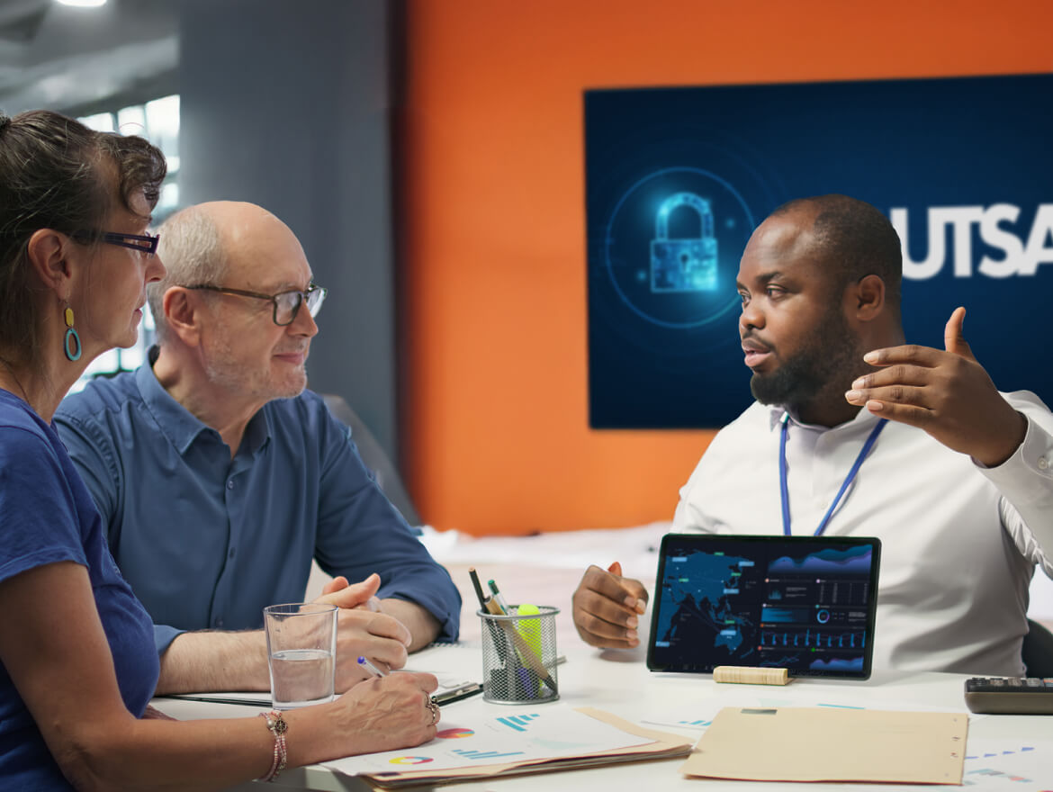 A group of people talking at a table with a tablet.