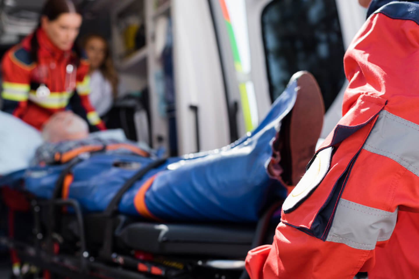 Paramedics assist an injured elderly person on a stretcher inside an ambulance