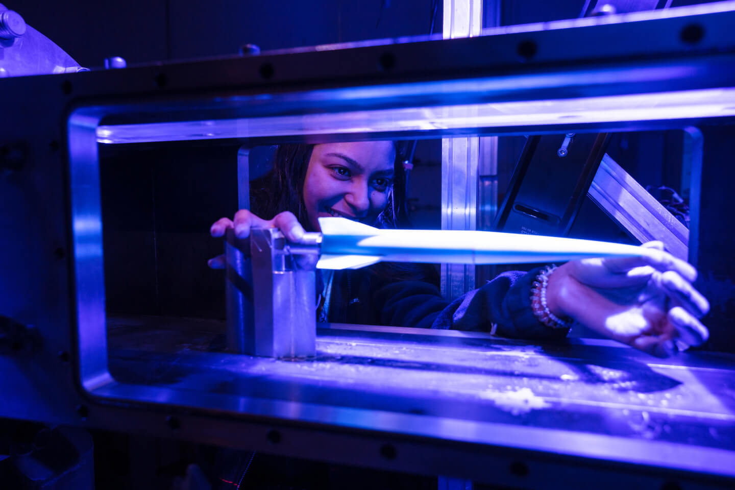 A person interacting with a glowing beam inside a laboratory environment, surrounded by blue lighting